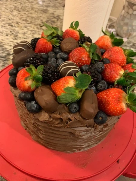 Chocolate cake topped with strawberries, blackberries, blueberries and chocolate-covered treats