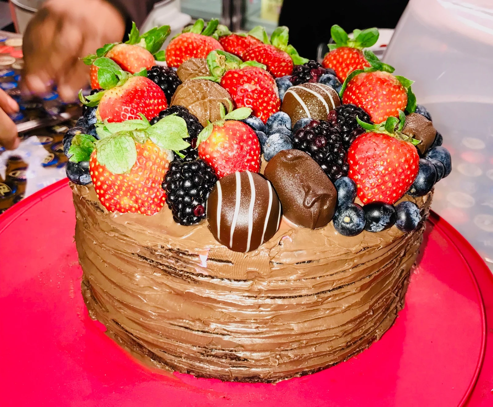 Chocolate celebration cake topped with strawberries, blackberries, blueberries and chocolate-covered treats